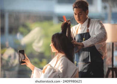 Asian Hairdresser giving treatment and barber occupation service, Professional hairstylist combing and using scissors cut woman's hair to young beautiful customer girl in beauty salon - Powered by Shutterstock