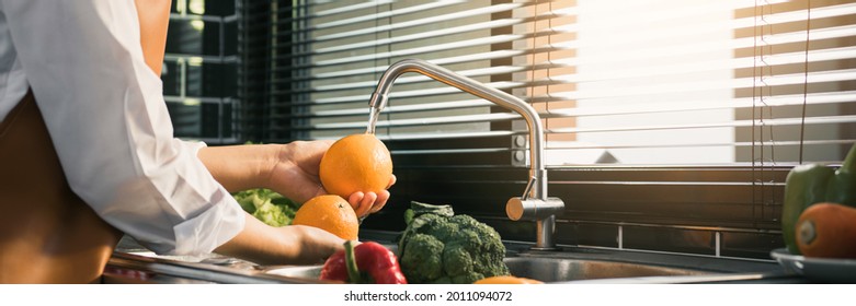 Asian hands woman washing fruit orange and preparation healthy food in kitchen.