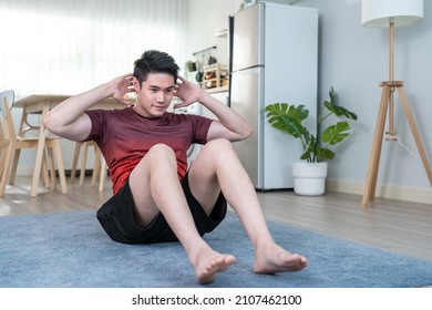 Asian Handsome Active Young Man Doing Sit Up On Floor In Living Room. Attractive Male In Sport Cloth Spend Leisure Activity Time To Exercise And Workout On Holiday At Home. Healthy Lifestyle Concept.