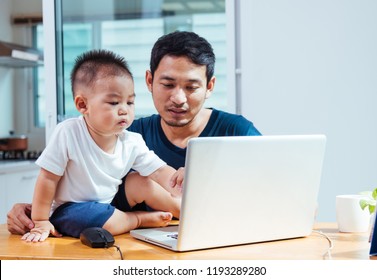 Asian handsome business man father parent working using laptop computer with he little baby son from home office
