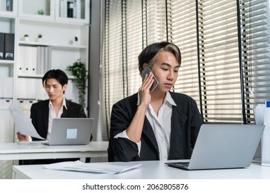 Asian Handsome Businessman Gay People Working In Office With Happiness. Attractive Male Lgbtq Collegues In Formal Wear Sitting On Table, Use Laptop Computer With Gay Pride And Confidence At Workplace.