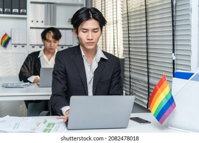 Asian Handsome Businessman Gay People Working In Office With Happiness. Attractive Male Lgbtq Collegues In Formal Wear Sitting On Table, Use Laptop Computer With Gay Pride And Confidence At Workplace.