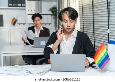 Asian Handsome Businessman Gay People Working In Office With Happiness. Attractive Male Lgbtq Collogues In Formal Wear Sitting On Table, Use Laptop Computer With Gay Pride And Confidence At Workplace.