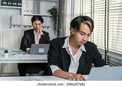 Asian Handsome Businessman Gay People Working In Office With Happiness. Attractive Male Lgbtq Collegues In Formal Wear Sitting On Table, Use Laptop Computer With Gay Pride And Confidence At Workplace.