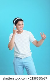 Asian Handsome And Cheerful Young Man Listening To Music, Isolated On Background