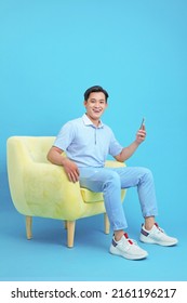 Asian handsome and cheerful young man using smart phone, sit on sofa, isolated on background - Shutterstock ID 2161196217
