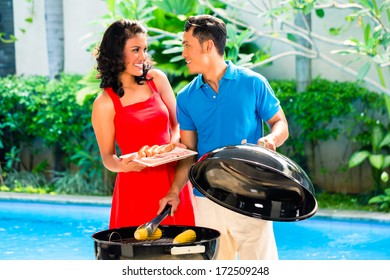 Asian Handsome Couple Having Barbecue Party Or BBQ Outside At The Pool With Grilled Corn Cobs