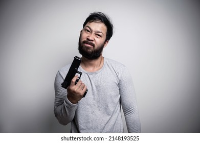 Asian Handsome Man Angry On White Background,Portrait Of Young Stress Male Concept,Hold Gun In Hand