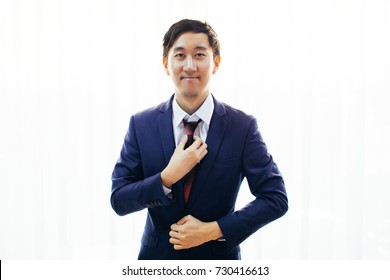 Asian Handsome Man Dressing Up In Formal Suit Over White Background With Copy Space