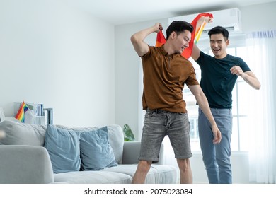 Asian Handsome Man Gay Family Holding LGBTQ Flag And Dance Together. Attractive Romantic Male Lgbt Couple Spend Time And Enjoy Listen To Music, Have Fun With Gay Pride Feeling And Carry Rainbow Flag.