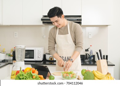 Asian handsome man looking recipe on laptop in kitchen at home - Powered by Shutterstock