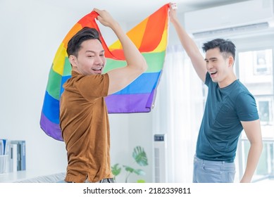 Asian Handsome Men Gay Family Holding LGBTQ Flag And Dancing Together. Attractive Romantic Male Lgbt Couple Spending Time And Enjoy Listen To Music, Have Fun With Gay Pride Feel And Carry Rainbow Flag