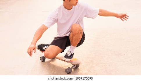 Asian Handsome Skater Man Kneel Surf Skateboard In Daylight Time, Summer Holiday.