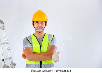 Asian Handsome Young Painter Working As A Painter Painting The Walls White Indoors With A Paint Roller In A New House Or Apartment Building