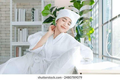 Asian happy beautiful young woman smiling wearing a towel and a white bathrobe sitting relaxed enjoy having fun, on the bed in bedroom spending time together at home, spa concept. - Powered by Shutterstock