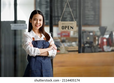 Asian Happy business woman is a waitress in an apron, the owner of the cafe stands at the door with a sign Open waiting for customers. Small business concept, cafes, and restaurants - Powered by Shutterstock