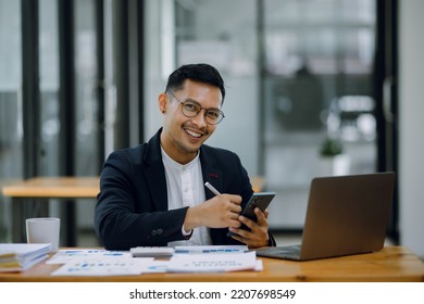 Asian Happy businessman working on smartphone with accounting documents at the table in office. Happy man working concept. - Shutterstock ID 2207698549