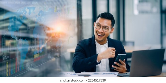 Asian Happy businessman working on smartphone and laptop with accounting documents at the table in office. Happy man working and  stock market concept. - Powered by Shutterstock