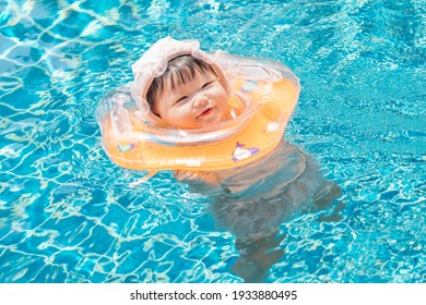 Asian happy cute baby swimming, smiling in a pool. 7 months baby in swimsuit with swim ring as concept of swimming, play, health, mood and motion of baby and kid development.