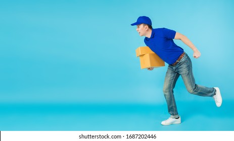 Asian happy delivery man wearing a blue shirt running and carrying paper parcel boxes isolated on on blue colour background with copy space.Concept of Postal delivery service. - Powered by Shutterstock