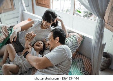 Asian happy family and child daughter laughing together on the bed enjoy holiday - Powered by Shutterstock