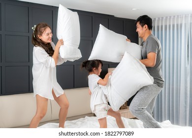 Asian happy family having funny pillow fight on white bed in bedroom for free time with father, mother and daughters feeling happy and family relationship in bedroom at home.
 - Powered by Shutterstock