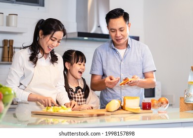 Asian Happy Family, Mother Cook Food For Dinner In Kitchen At House. Loving Father And Young Little Kid Daughter Have Fun Spending Time Together, Look At Mom Making Food. Activity Relationship At Home