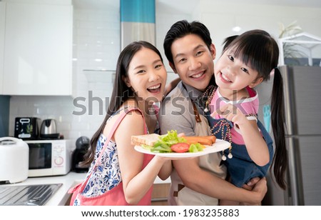 Asian happy family preparation breakfast together in kitchen After cooking, take a picture and look at the camera together.