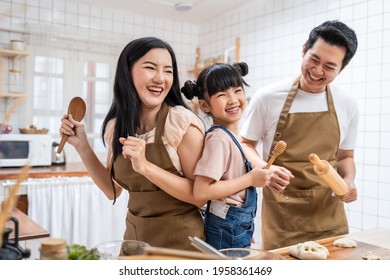 Asian Happy Family Stay At Home In Kitchen Spend Time Together Baking Bakery And Foods. Little Kid With Parents, Father And Mother Dancing And Laughing, Enjoy Parenting Activity Relationship In House.