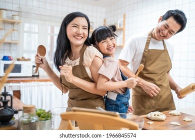 Asian Happy Family Stay At Home In Kitchen Spend Time Together Baking Bakery And Foods. Little Kid With Parents, Father And Mother Dancing And Laughing, Enjoy Parenting Activity Relationship In House.