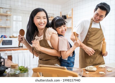 Asian happy family stay home in kitchen bake bakery and dance together. Fatherand mother spend free time with young little girl daughter make food, Kid enjoy parenting activity relationship in house. - Powered by Shutterstock