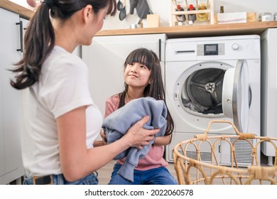 Asian Happy Family Stay Home, Mother Teach Daughter Wash Dirty Clothes. Young Little Cute Girl Child Help And Learn From Parent Mom To Put Laundry In Washer Appliance At Home. Domestic-Housekeeping.