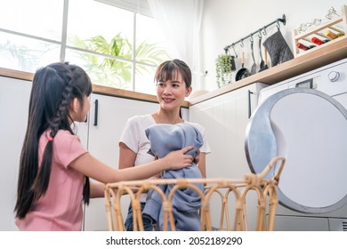 Asian Happy Family Stay Home, Mother Teach Daughter Wash Dirty Clothes. Young Little Cute Girl Child Help And Learn From Parent Mom To Put Laundry In Washer Appliance At Home. Domestic-Housekeeping.