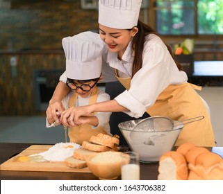 Asian Happy Family Wears Chef Hat And Apron Cooking Food In Kitchen.Mother And Son Fun Cooking Food.Mother And Child Are Happy To Do Activities Together In The Kitchen.