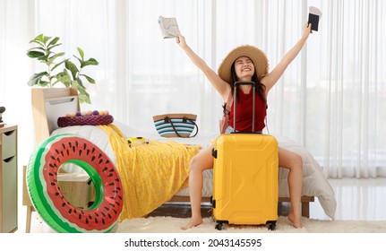 Asian Happy Female Traveler Imagines For Happiness Holiday With Happy Face, Holding Passport, Airplane Travel Flight Tickets And Paper Map Overhead With Yellow Trolley Luggage Ready For Vacation Trip.