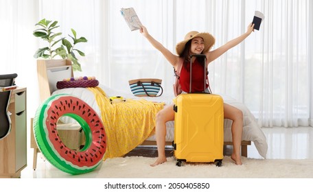 Asian Happy Female Traveler Imagines For Happiness Holiday With Happy Face, Holding Passport, Airplane Travel Flight Tickets And Paper Map Overhead With Yellow Trolley Luggage Ready For Vacation Trip.