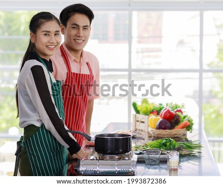 Asian happy handsome boyfriend and friendly beautiful skilled girlfriend lovers couple cooking Tom Yam Kung together in kitchen
