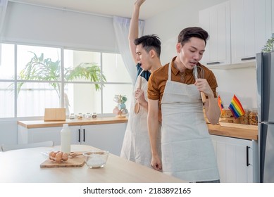 Asian Happy Handsome Man Gay Couple Sing And Dance Together In Kitchen. Attractive Romantic Male Lgbt Couple Wear Apron, Spending Free Leisure Time And Enjoy Listen To Music And Cooking Foods In House