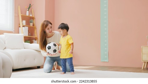 asian happy mother and her child son are playing with soccer ball together in living room at home - Powered by Shutterstock