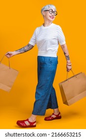 Asian Happy Senior Female Woman Tattoo Holds Colourful Shopping Packages Standing On Yellow Background Studio Shot, Close Up Portrait Old Female Hand Hold Shopping Bags Enjoy Shopping With Joyful