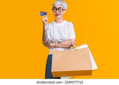 Asian happy senior female woman tattoo holds colourful shopping packages standing on yellow background studio shot, Close up Portrait old female hand hold shopping bags enjoy shopping with joyful - Shutterstock ID 2249577713