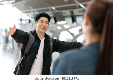 Asian Happy And Smile Man Running Open Arms To Embrace Friend Or Girlfriend At Arrival Gate In Airport Terminal. Welcome Back Home From Study Or Working Abroad. 