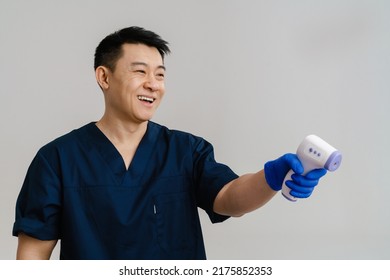 Asian Health Worker Laughing While Using Forehead Thermometer Isolated Over White Background