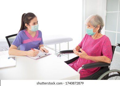 Asian Healthcare Worker Screening Old Patient In Hospital, She Assess And Write Report On Medical Record Chart, Elderly Health Check Up, They Wear Surgical Mask, Corona Virus Protection