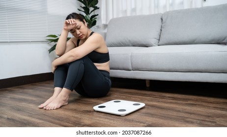 Asian healthy woman bored of dieting Weight loss fail  Fat diet and scale sad asian woman Upset on weight scale at home weight control.