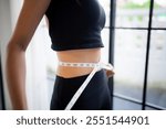 Asian healthy woman dieting Weight loss. Slim woman measuring waist with measure tape after diet at home weight control