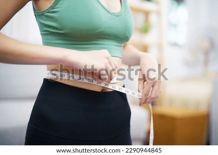 Asian healthy woman dieting Weight loss. Slim woman measuring waist with measure tape after diet at home weight control