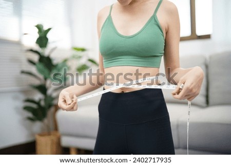 Asian healthy woman dieting Weight loss. Slim woman measuring waist with measure tape after diet at home weight control