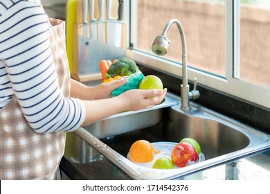 Asian healthy woman washing an apple and other fruit above kitchen sink and applying a fruit / vegetable with soap to eliminate the chances of contamination COVID-19.
 - Powered by Shutterstock