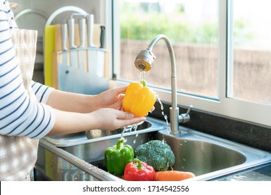 Asian healthy woman washing yellow bell pepper and other vegetable above kitchen sink and cleaning a fruit / vegetable with water to eliminate the chances of contamination COVID-19.
 - Powered by Shutterstock